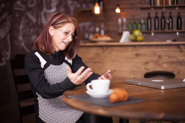 Volwassen zakenvrouw verbaasd tijdens het gebruik van haar telefoon — Stockfoto