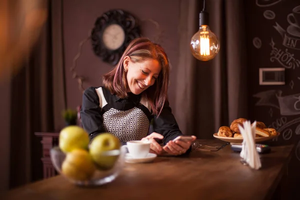 Взрослая деловая женщина смеется, глядя в телефон — стоковое фото