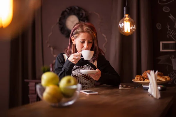 막대기 카운터에 앉고 있는 동안 그녀의 잔의 커피를 즐기고 성공적인 성인 사업가 — 스톡 사진