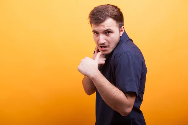 Aggressiver junger Mann zeigt Fäuste auf gelbem Hintergrund — Stockfoto