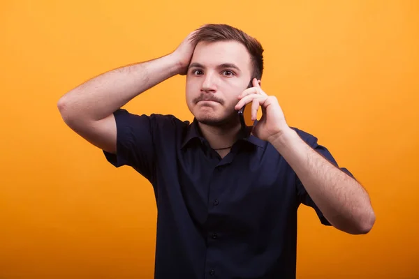 Jeune homme avec la main sur la tête en parlant au téléphone — Photo