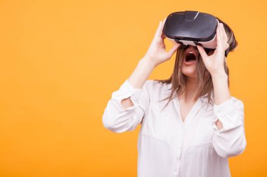 Sanal gerçeklik deneme güzel genç kız sarı arka plan üzerinde koruyucu gözlük