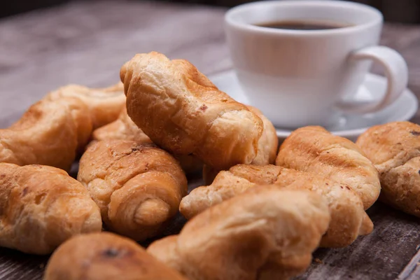 Freshly baked croissants on rustic wooden table with cup of coffee — Stock Photo, Image