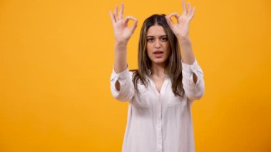 Mutlu gülümseyen kadın gösterir Tamam sarı arka plan üzerinde oturum