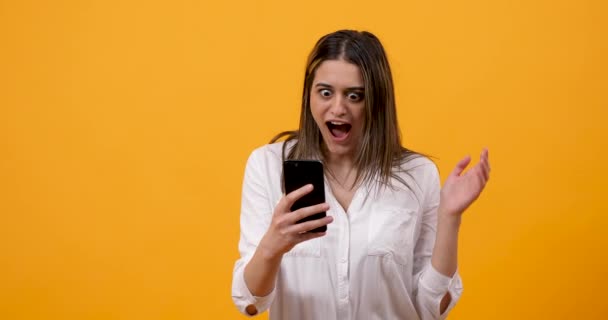 Mujer joven conmocionada y emocional mirando el teléfono — Vídeo de stock