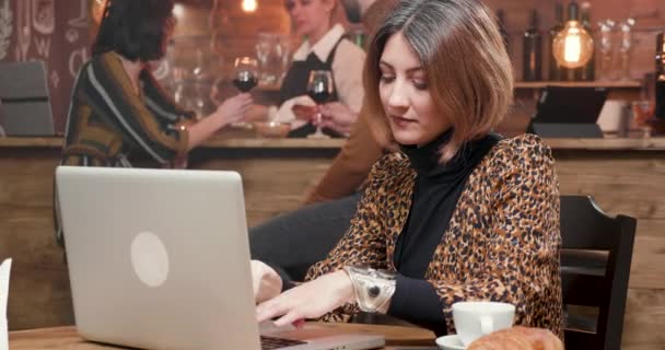 Empresaria escribiendo un texto en su portátil mientras trabaja en una cafetería — Vídeos de Stock