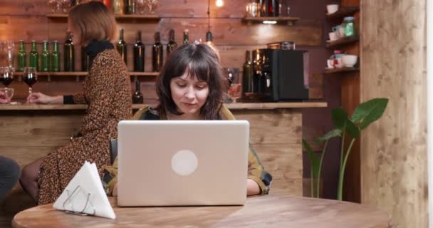 Menina bonita digitando em seu computador enquanto está sendo servido café em uma cafeteria — Vídeo de Stock