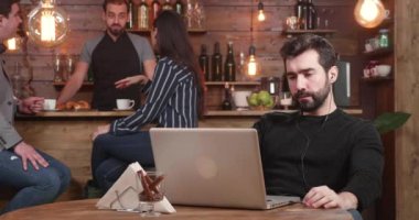 Kaydırıcıyı soldan beyaz bir erkek rught için vurdu. Genç bir kahve dükkandan Uzaktan çalışırken onun laptop ekranında görünen adam sakallı. Vintage tarzı meşgul Restoran.