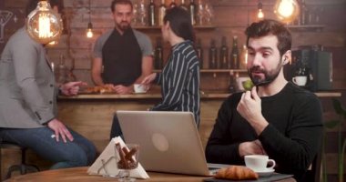 Bir kahve dükkanında çalışırken onun laptop bir online arama sahip bir adam.