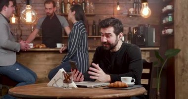 Bir kafede onun kahve servisi sırasında video çağrısı yapan genç yakışıklı adam