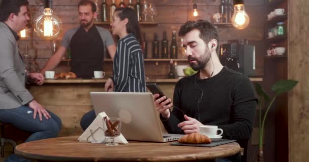 Joven freelancer respondiendo a una llamada en su smartphone y cierra su laptop — Vídeo de stock