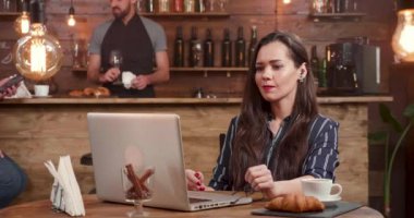 Genç kadın onu laptop süre küçük bir restoranda, bir müzik video izlerken