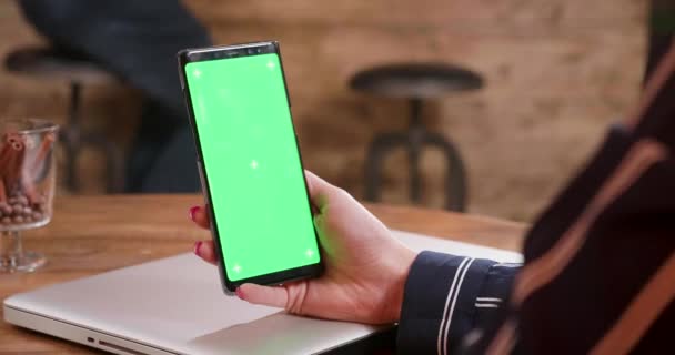 Una mano de mujer joven sosteniendo un smartphone con pantalla verde — Vídeos de Stock