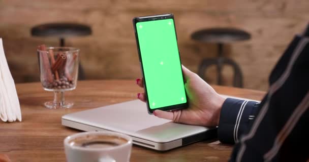 Slide tiro da direita para a esquerda de uma mão de mulheres segurando um smartphone tela verde — Vídeo de Stock