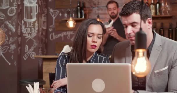 Jonge vrouw voor het beantwoorden van een telefoongesprek terwijl tijdens een bijeenkomst in een cofee winkel — Stockvideo