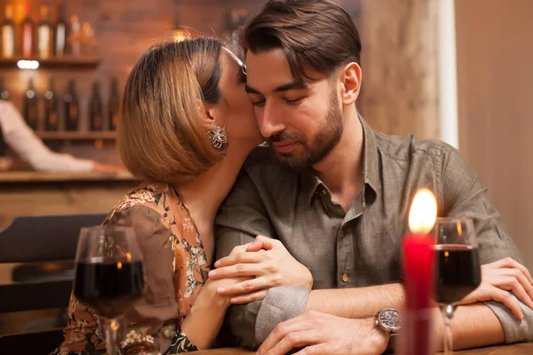 Mujer joven besa suavemente la mejilla de su novio en una cita para cenar —  Fotos de Stock