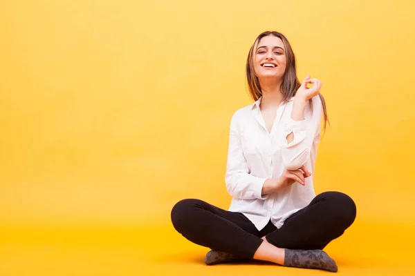 Mooie jonge vrouw die lacht tijdens het zitten op gele achtergrond — Stockfoto