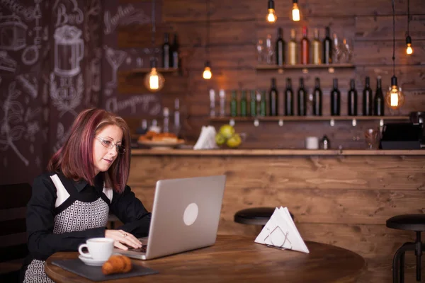 Zakenvrouw bezig met haar laptop in een gezellige coffee shop — Stockfoto