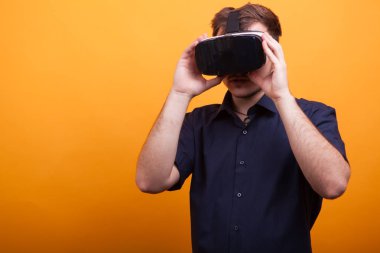 Komik güzel genç adam mavi gömlek ve Vr kulaklığı sarı arka plan üzerinde seyir