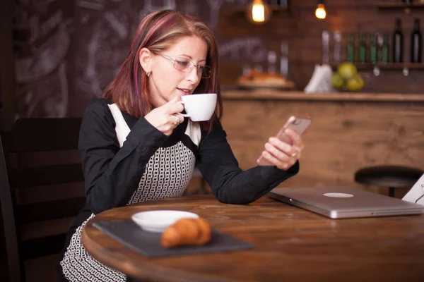 Volwassen zakenvrouw, lezen van e-mails van haar telefoon — Stockfoto