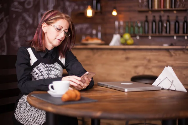 Succesvol zakenvrouw controleren haar telefoon naast Franse croissant — Stockfoto