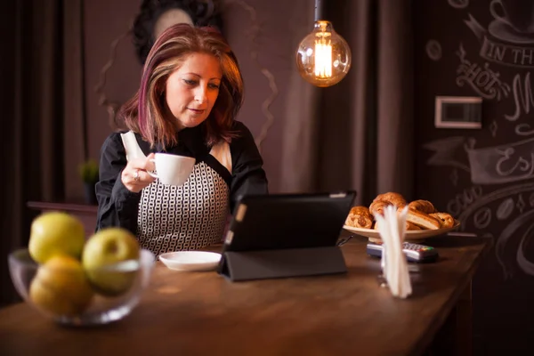 Volwassen zakenvrouw zoeken op haar tablet in een vintage koffieshop — Stockfoto