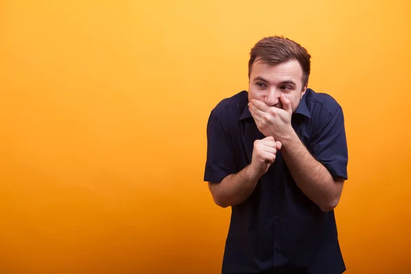 Único riso atraente jovem em camisa azul sobre fundo amarelo — Fotografia de Stock