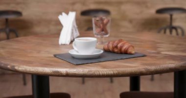 Bir kahve ve çörek minimalist bir kompozisyon içinde karanlık bir taş tepsi üzerinde slayt