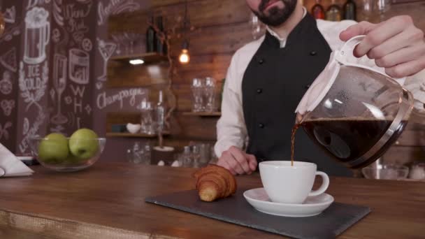 Barista muž drží džbán čerstvé připravené kávy a nalévá prázdný pohár — Stock video