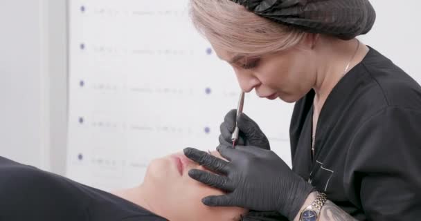 Jovem cosmetologista loira realizando um procedimento em uma cliente feminina — Vídeo de Stock