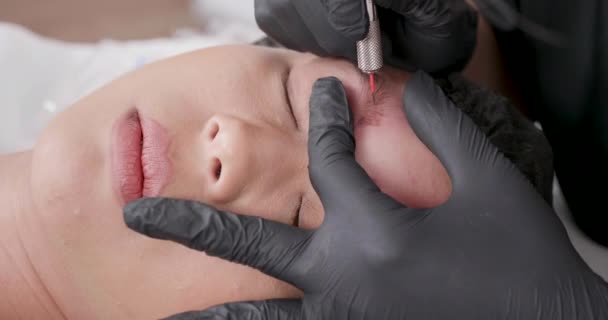 Вид сверху на лицо молодой женщины в салоне красоты, удаляющей татуировку брови — стоковое видео