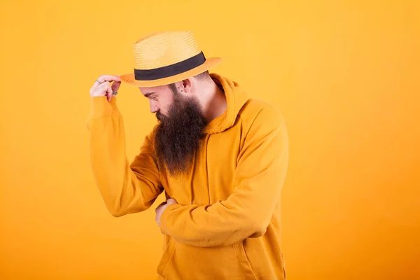 Attraktiver bärtiger Mann mit Hut vor gelbem Hintergrund — Stockfoto