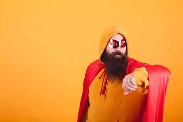 Hipster com barba longa vestida com traje de super-herói olhando para o fundo amarelo — Fotografia de Stock