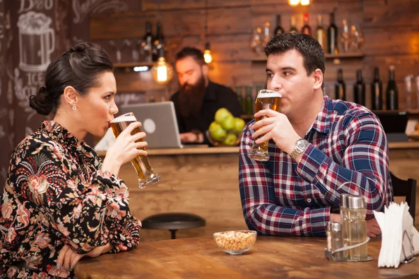 Casal romântico bebendo cerveja em um pub hipster e fazendo um brinde . — Fotografia de Stock