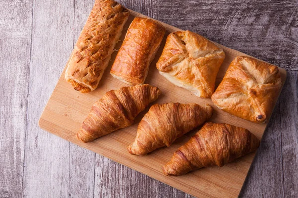 An assortment of freshly baked pastry aligned on cutting board — Stock Photo, Image