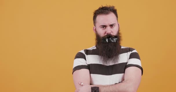 Bebaarde jonge man met een zwarte duck tape op zijn mond — Stockvideo
