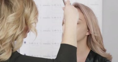 Pistole cilt kusurlarını kullanacak sarışın makyaj sanatçısı