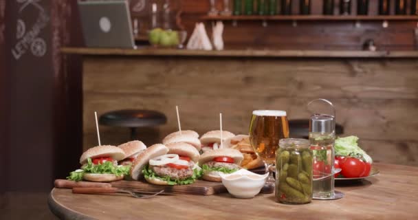 Uma mesa de madeira com hambúrgueres em tábuas de madeira na frente de um bar — Vídeo de Stock