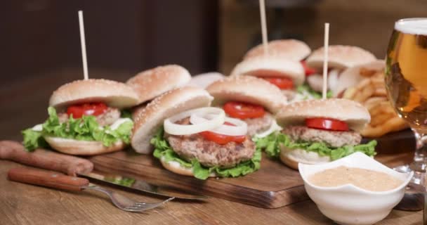 Hamburguesas con papas fritas, salsa y cerveza en un vaso — Vídeo de stock