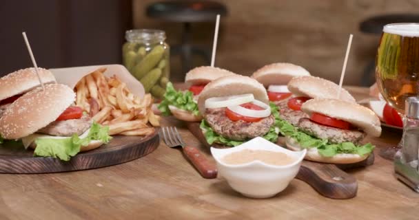 Tiro de paralaxe liso de ampla seleção de hambúrgueres em uma mesa redonda de madeira — Vídeo de Stock
