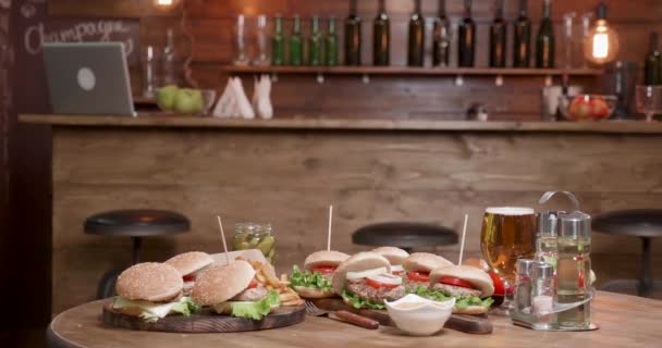 Gran selección de hamburguesas en mesa de madera frente a un bar — Vídeos de Stock