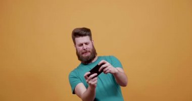 Genç çekici adam eğlenceli bir oyun onun smartphone üzerinde çalış.