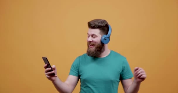 Красивый молодой человек слушает музыку на своем смартфоне и танцует — стоковое видео