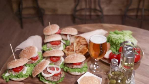 Molti hamburger, una bottiglia di sottaceti e un bicchiere di birra bionda — Video Stock