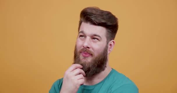 El hombre acaricia su barba pensando en algo y de repente se hace una idea — Vídeos de Stock