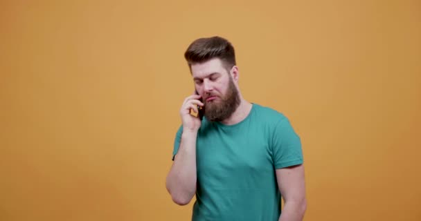 Aantrekkelijke jonge man met mooie baard verwikkeld in een telefoongesprek — Stockvideo