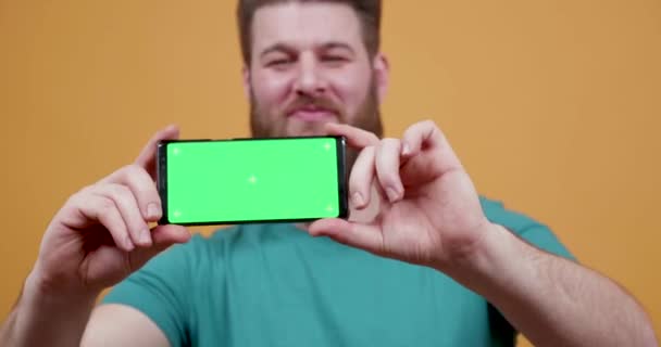 Hombre orgullosamente muestra su teléfono con pantalla verde en — Vídeos de Stock