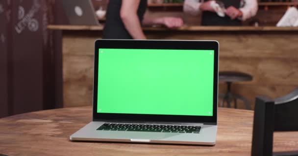 Laptop with green screen on the display in cozy cafe — Stock Video