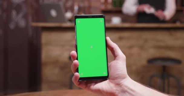 視差動的スライド ショット緑色の画面で現代の携帯電話を保持している男性の手 — ストック動画