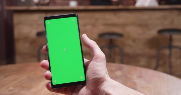 Jatten op een telefoon met groen scherm in een vintage café — Stockvideo